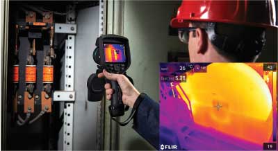 An inspector using their FLIR EXX thermal imager inside an electrical panel.